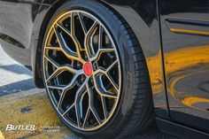 the front wheel of a black car with gold rims