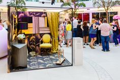 a group of people standing around a room filled with furniture and decor on the floor