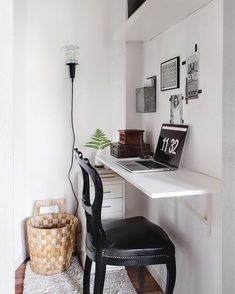 a white desk with a black chair in front of it and pictures on the wall