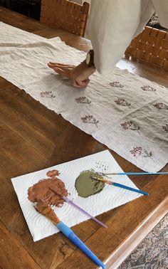 someone is painting on paper with paintbrushes and some other things next to them