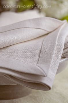 a close up of a white cloth on a table with some flowers in the background