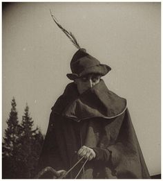 an old photo of a man in a cape and hat with a dog on a leash