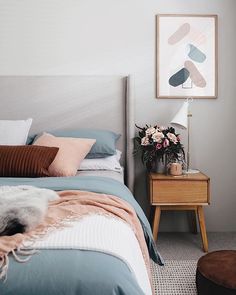 a bed room with a neatly made bed and a painting on the wall above it