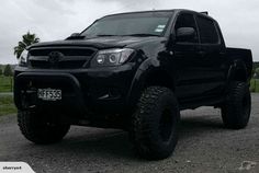 a black truck is parked on the gravel