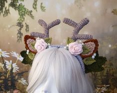 a white wig wearing a crocheted deer headband with flowers on it's ears