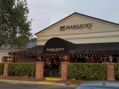 the front of a restaurant with lights strung from it's roof