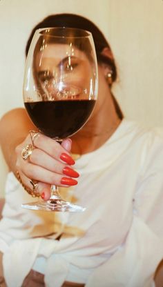 a woman holding a glass of wine up to her face