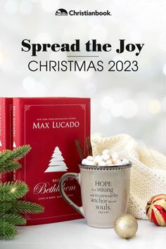 a coffee mug with hot cocoa in it next to some christmas decorations and a book