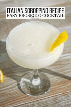 a close up of a drink in a glass with a lemon wedge on the rim