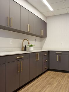 a kitchen with brown cabinets and white counter tops in an office building or conference room