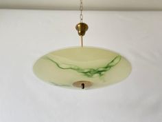 a green and white glass light hanging from a ceiling