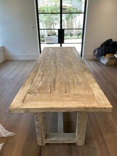 a wooden table sitting on top of a hard wood floor next to a window in a room