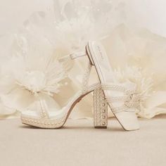 a pair of white high heeled shoes sitting on top of a flower