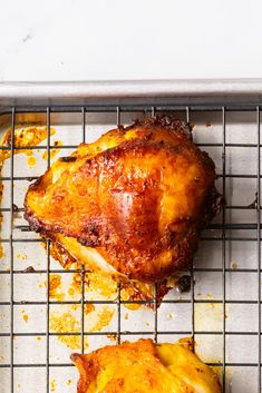 two pieces of chicken sitting on top of a cooling rack next to another piece of meat