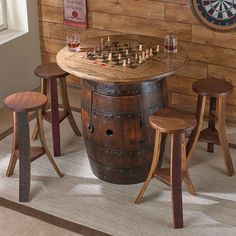 a wooden barrel table with stools and chess board on it in front of a wood paneled wall