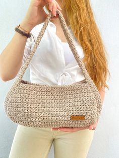 a woman holding a crocheted purse in front of her face while talking on the phone