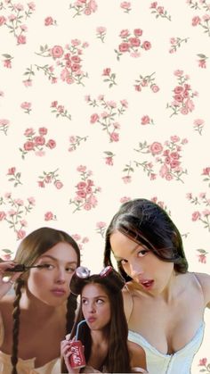 three women are posing for the camera in front of a floral wallpaper with pink roses