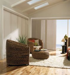 a living room filled with furniture and a large window overlooking the ocean on top of a wooden floor