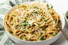 a white bowl filled with pasta and parmesan cheese on top of a table