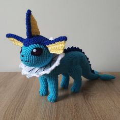 a crocheted blue and yellow dragon doll on a wooden table with text overlay