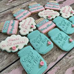 decorated cookies are sitting on a wooden table with pink and blue frosted cookies in the shape of mason jars