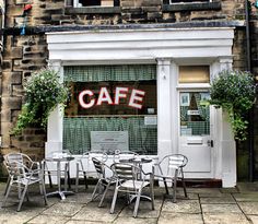 an outside cafe with tables and chairs in front of the building that has it's door open