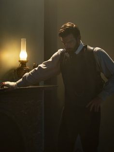 a man standing next to a table with a lamp on it