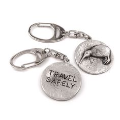 two metal key chains with the words travel safely written on them and an image of a seagull