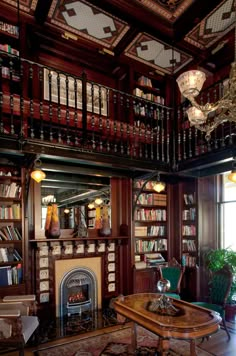 the library has many bookshelves and tables with chairs around it in front of a fireplace