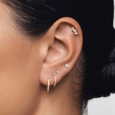 a woman wearing three different ear piercings on her left ear and the other one is in