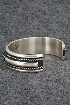 This sterling silver bracelet was made by Navajo silversmith Leander Tahe. The inside is signed L. Tahe and stamped sterling.Size: 5 5/8" (will fit up to a 7 1/8" wrist)Gap: 1 1/2"Width: 3/4"Free shipping on all orders! We ship with USPS and always include tracking. All orders ship within a day of payment.Returns are accepted up to 30 days after you receive your order. Just send us a message. Our shop offers cash back or store credit. The item must be returned in new condition. Southwestern Sterling Silver Polished Bangle Bracelet, Southwestern Sterling Silver Bangle With Polished Finish, Southwestern Polished Sterling Silver Bangle, Sterling Silver Southwestern Bracelet With Polished Finish, Southwestern Silver Cuff Bracelet With Oyster Detail, Native American Jewelry, Free Jewelry, Sterling Silver Bracelets, Silver Bracelet