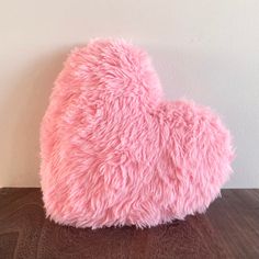 a pink heart shaped pillow sitting on top of a wooden table