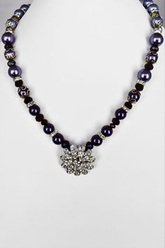 Purple Beaded Necklace This beaded necklace is an ombre design in shades of purple lightening to lavendar and lilac in glass and silver beads.  It measures 19.5 inches across and comes with a 2 inch extender chain which will increase it to 21.5 if the extra length is needed.  The pendant is a sparkly crystal in a flower shape and measures 1.25 inches across. This would be great to dress up any outfit, with a pair of favorite jeans, a white blouse, a Red Hat Ladies outfityou name it....it will look great! As always, it is a one of a kind piece.  As such, it will make a great gift.  Whether for a birthday, anniversary, Christmas or Mother's day, you will be sure to love it!  If you're buying an item as a gift, I'm happy to send it directly to the recipient, gift wrapped with a card from you. Purple Beaded Chain Necklace With Round Beads, Purple Necklaces With Polished Beads For Party, Purple Beaded Party Necklace, Elegant Purple Necklace With Large Beads, Elegant Large Purple Beads, Purple Beaded Crystal Necklaces For Party, Adjustable Beaded Purple Pearl Necklace, Adjustable Purple Pearl Necklace With Round Beads, Purple Beaded Necklace With Large Beads For Party