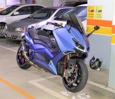 a blue motorcycle parked in a parking garage next to other cars on the side of the road