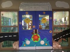 two doors with faces painted on them in front of a book store display case filled with children's books