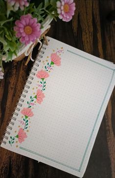 an open notebook with pink flowers on it next to a bouquet of daisies and other flowers