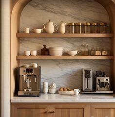 a coffee maker and some cups on a shelf in a kitchen with marble counter tops