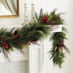 a fireplace decorated for christmas with greenery and pine cones