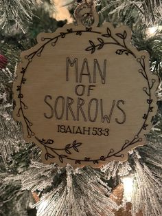 a wooden ornament with the words man of sorows on it hanging from a christmas tree