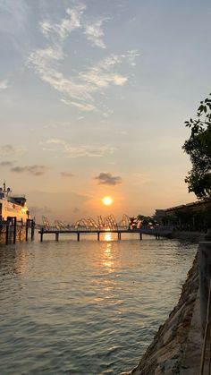 the sun is setting behind a bridge over water