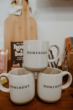 three white coffee mugs sitting on top of a wooden table