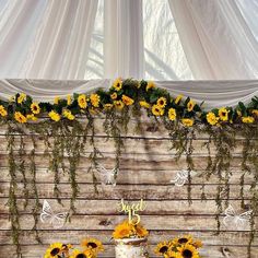 a cake with sunflowers on it sitting in front of a wooden wall and window