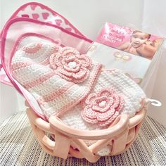 a pink crocheted baby's blanket and booties in a basket