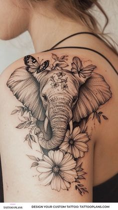 an elephant and flowers tattoo on the back of a woman's shoulder is shown