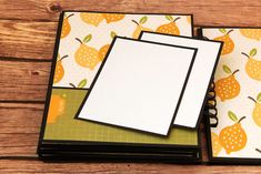 two notebooks with papers on top of them sitting next to each other in front of a wooden table