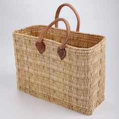 a wicker basket with leather handles on a white background