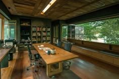 an office with wood floors and large windows overlooking the trees in the distance is shown