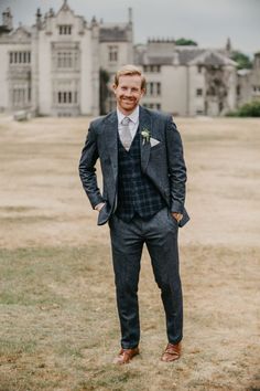 a man standing in front of a large building wearing a suit and tie with his hands in his pockets