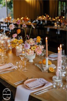 the table is set with candles, plates and flowers in vases on each side