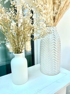 two white vases with dried flowers in them